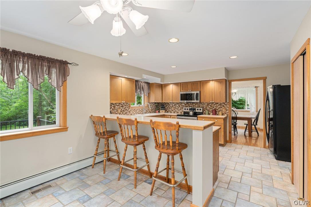 3220 Winding Road Kintnersville, PA 18930 - Photo 28 of 50 a kitchen with stainless steel appliances granite countertop a stove a sink a refrigerator white cabinets with a dining table and chairs