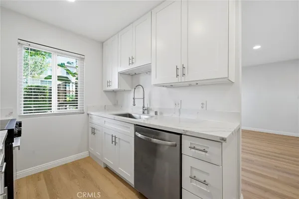 a kitchen with granite countertop white cabinets and a sink