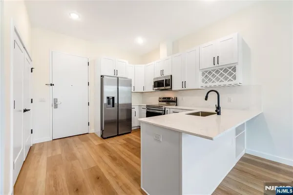 a kitchen with stainless steel appliances a refrigerator sink and white cabinets