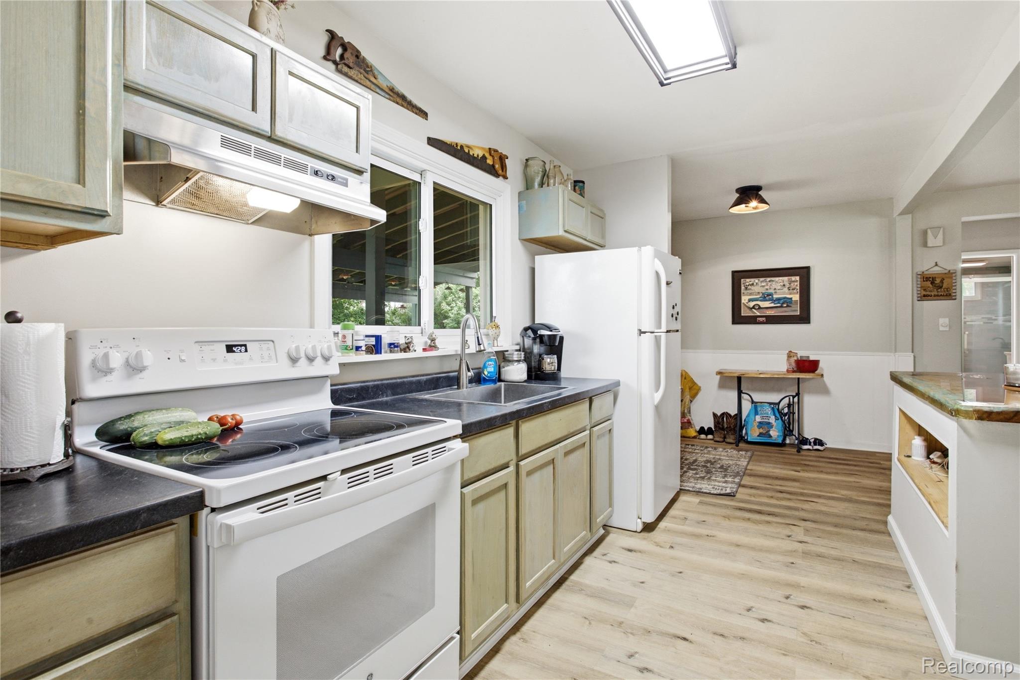 4945 Miller Road Ann Arbor, MI 48103 - Photo 13 of 42 Kitchen featuring light wood-finish flooring, recessed lighting, white appliances, and a skylight