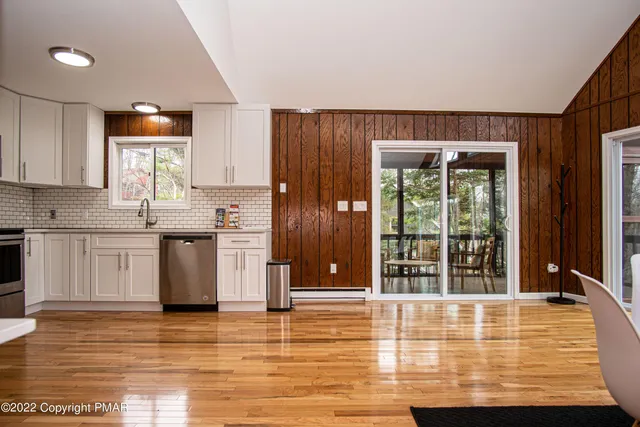 a living room with couches chairs and kitchen view with wooden floor