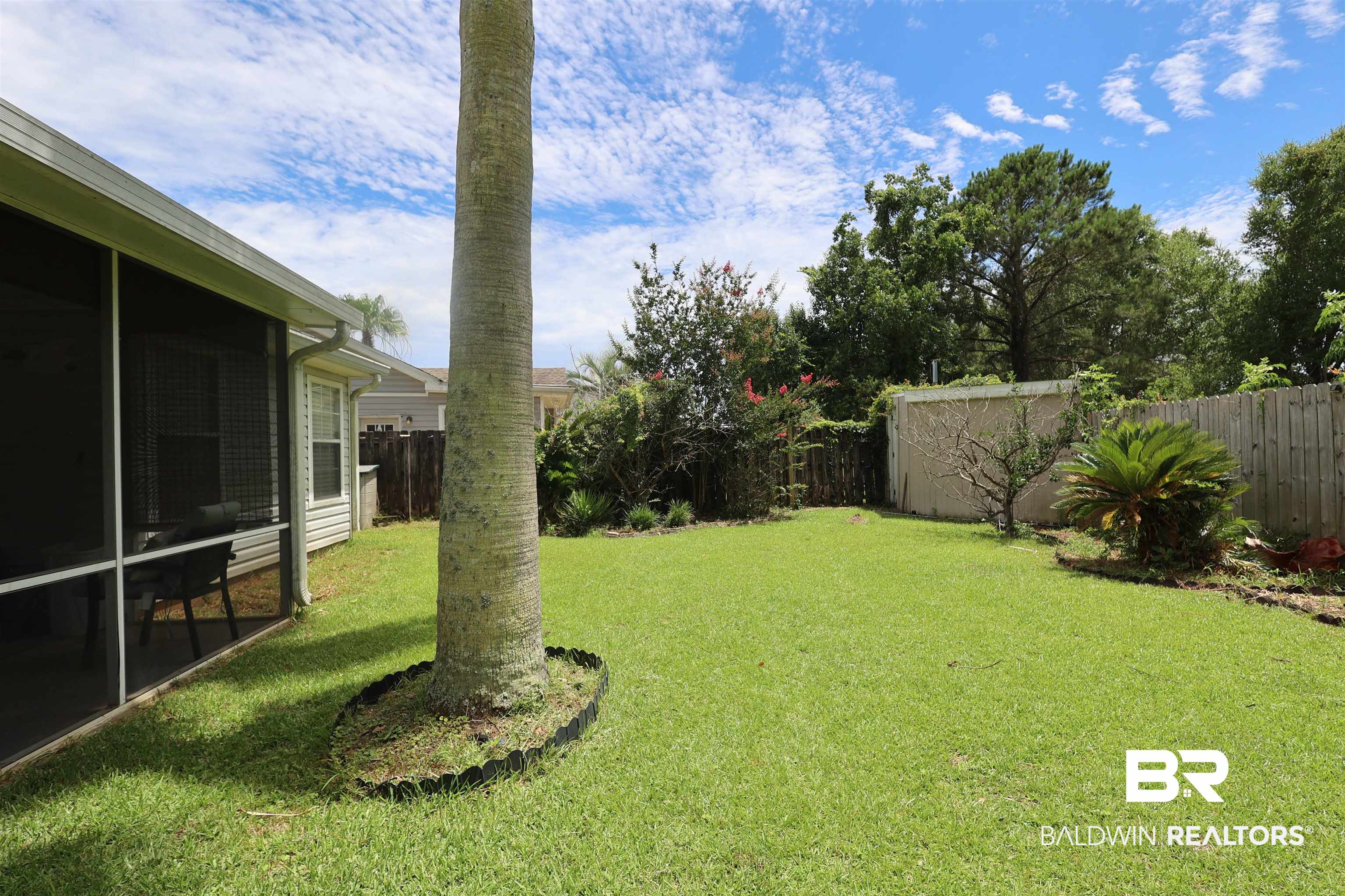 7790 Audubon Drive Foley, AL 36535 - Photo 37 of 39 Spacious backyard featuring a substantial palm tree, screened patio, manicured lawn, and wood privacy fencing