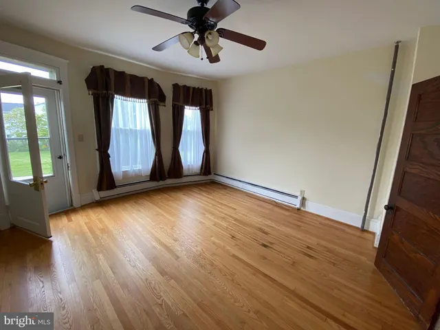 a view of an empty room with window and wooden floor