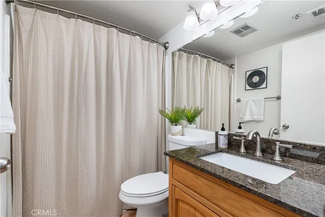 a bathroom with a granite countertop sink and a mirror with toilet