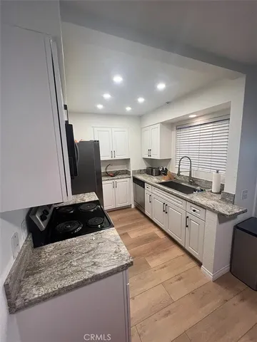 a kitchen with granite countertop a sink stainless steel appliances and cabinets