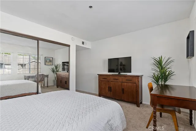 a bedroom with a large bed and a flat tv screen on dresser