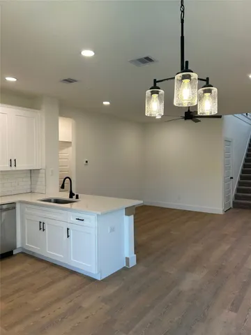 a kitchen with kitchen island cabinets a sink and wooden floor