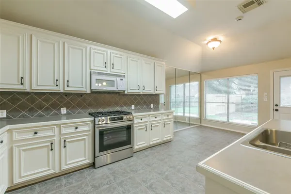 a kitchen with white cabinets appliances and a sink