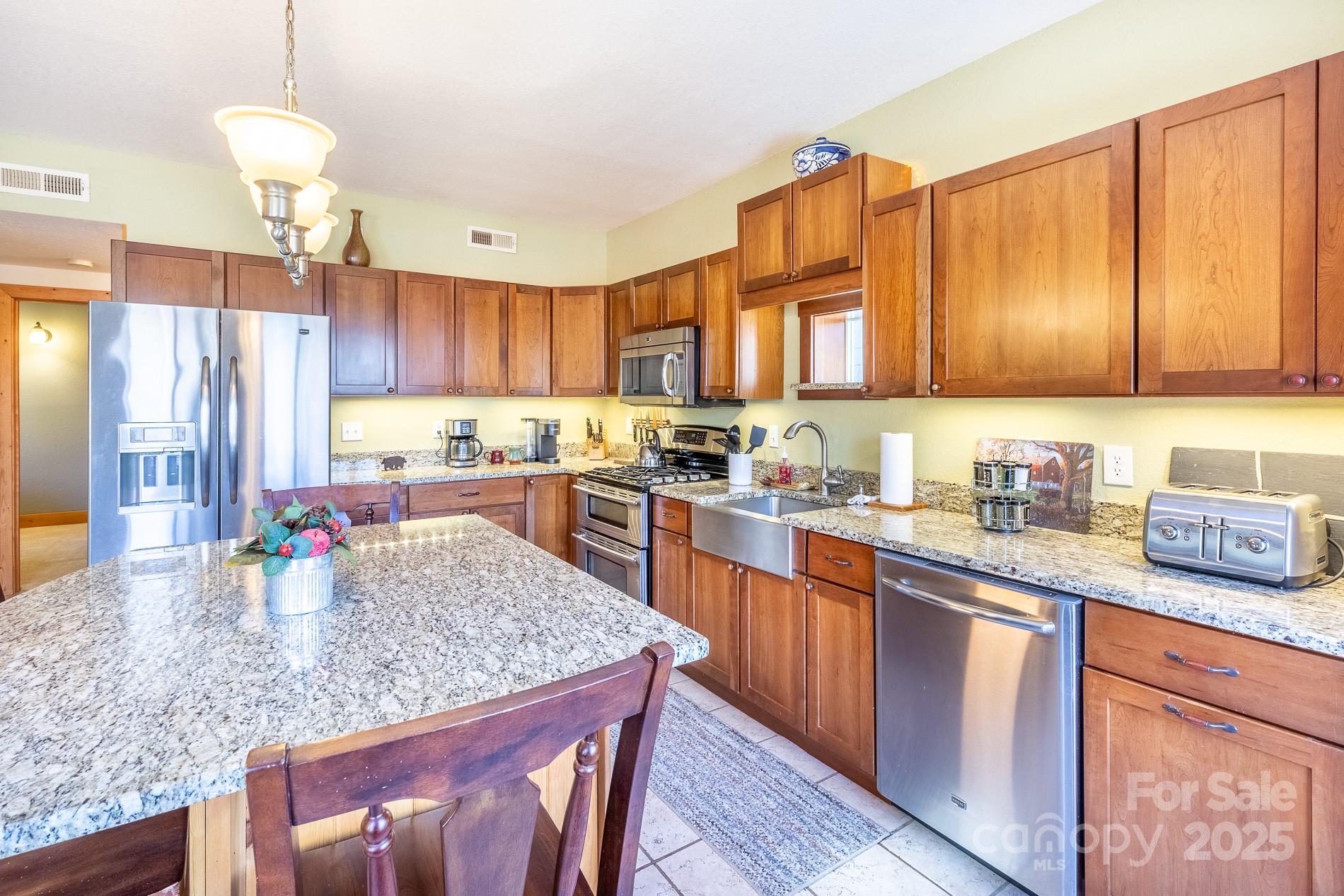 283 Walnut Cv Ridge Bryson City, NC 28713 - Photo 26 of 42 a kitchen with kitchen island granite countertop wooden cabinets a refrigerator a stove a oven and a dining table
