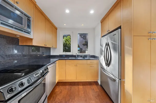 a kitchen with stainless steel appliances granite countertop a refrigerator a sink and a stove