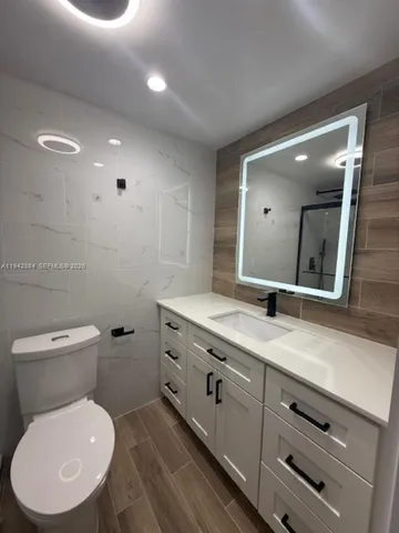 a bathroom with a granite countertop sink toilet and shower