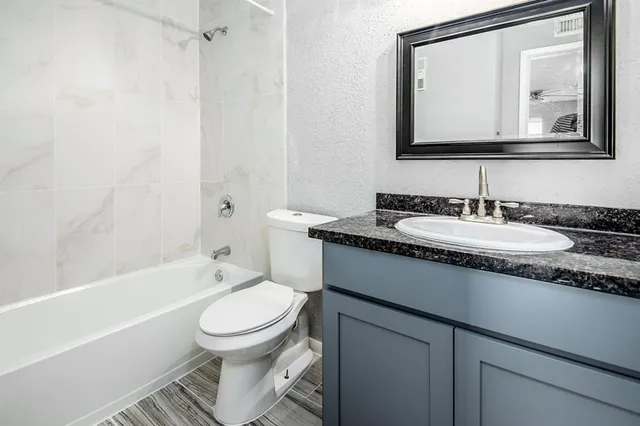 a bathroom with a granite countertop toilet sink and mirror