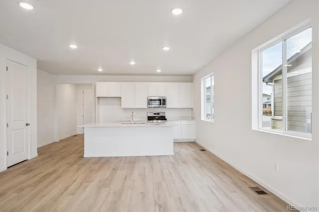 a kitchen with stainless steel appliances a sink stove and wooden floor