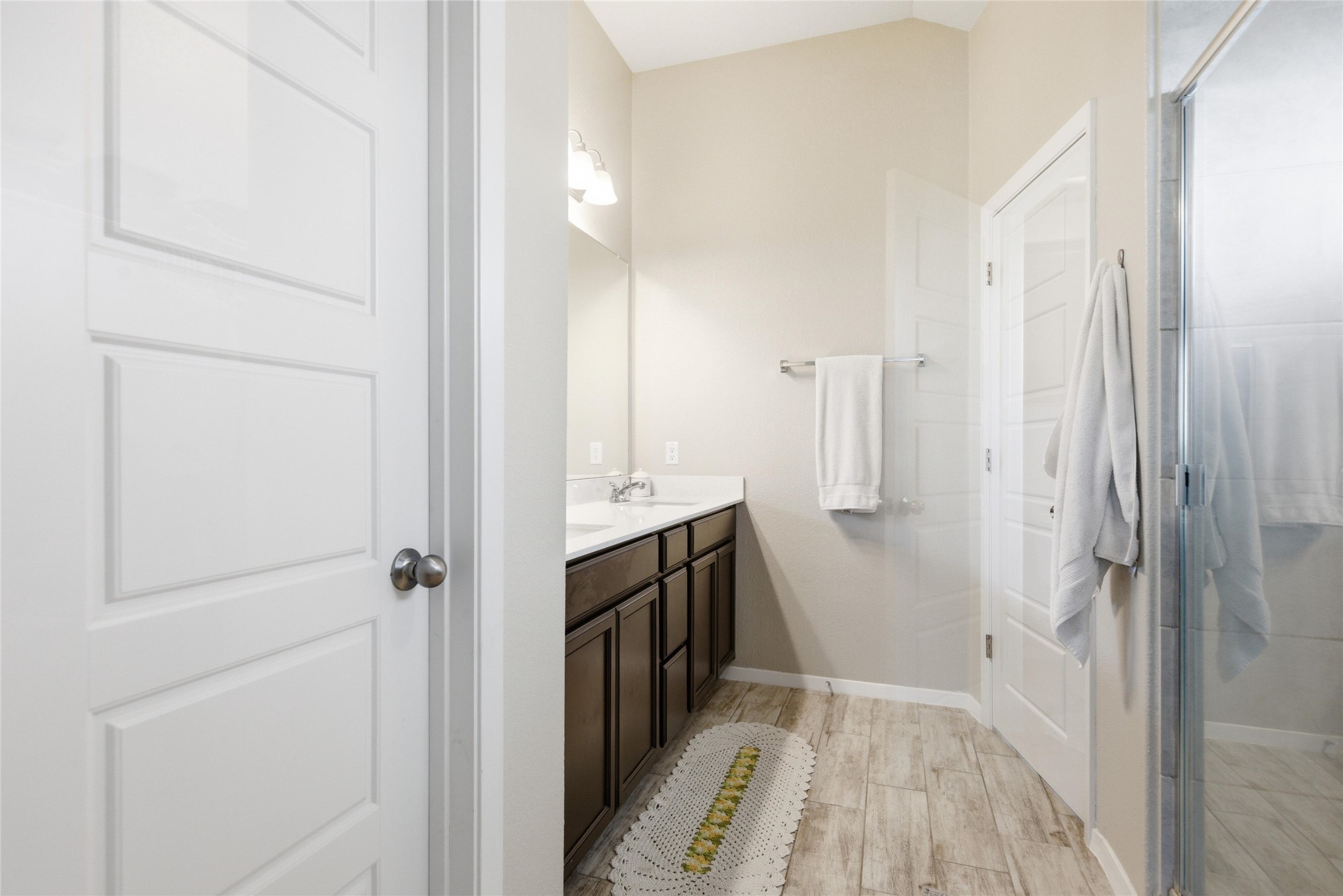 269 Gaida Loop Georgetown, TX 78628 - Photo 13 of 20 Bathroom with a shower stall, double vanity, light wood-style flooring, and vaulted ceiling