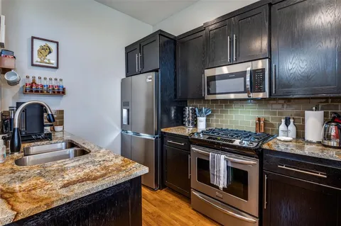 a kitchen with kitchen island granite countertop stainless steel appliances and wooden cabinets