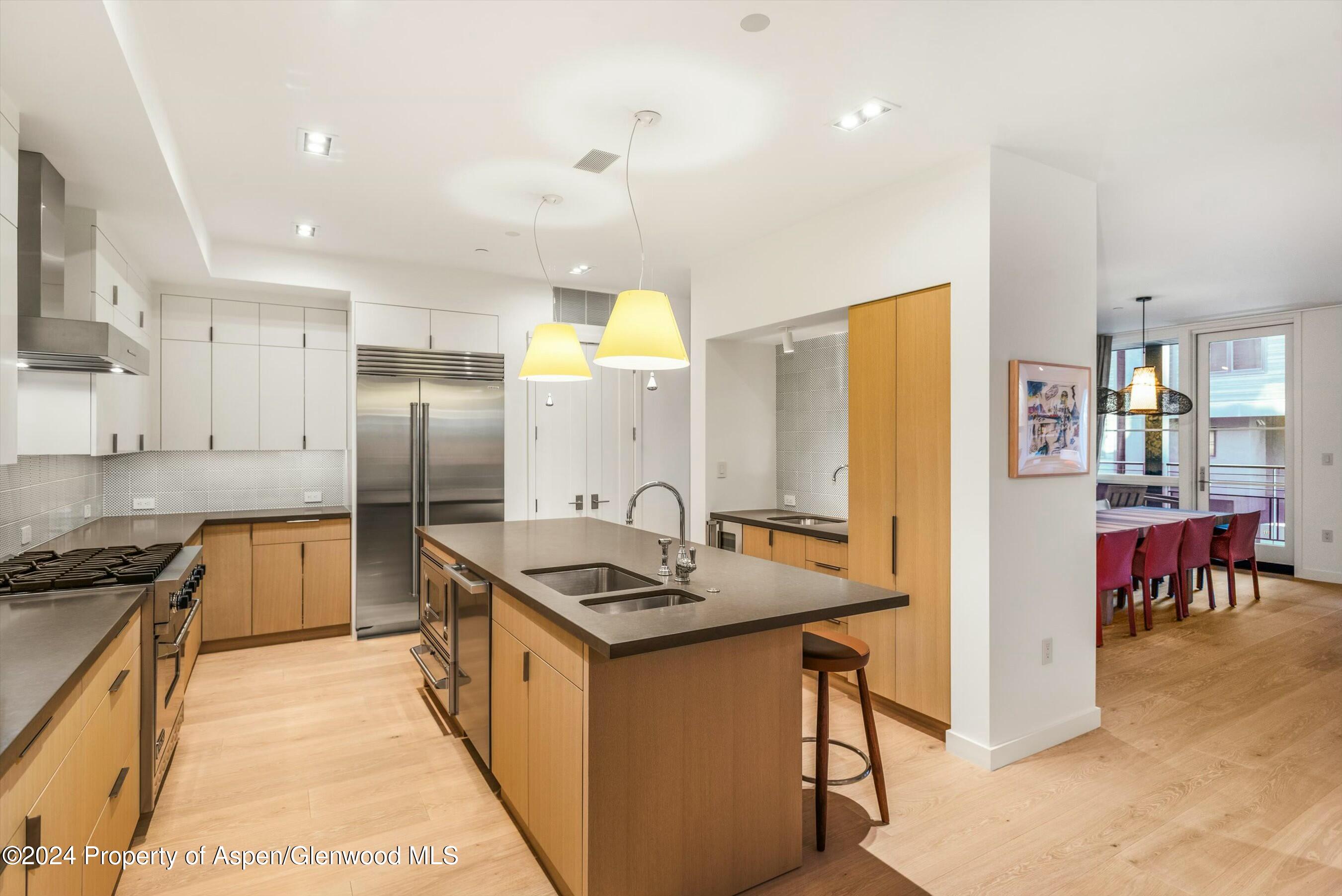 233 East Cooper Avenue, Unit 207 Aspen, CO 81611 - Photo 12 of 45 a kitchen with stainless steel appliances granite countertop a refrigerator a stove and a sink with wooden floor