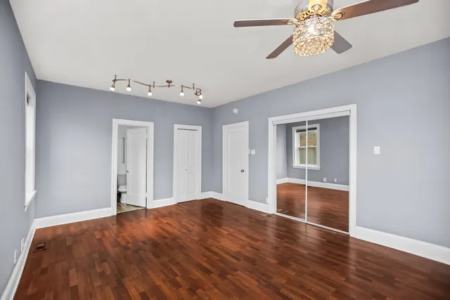 a bedroom with wooden floor and ceiling fan