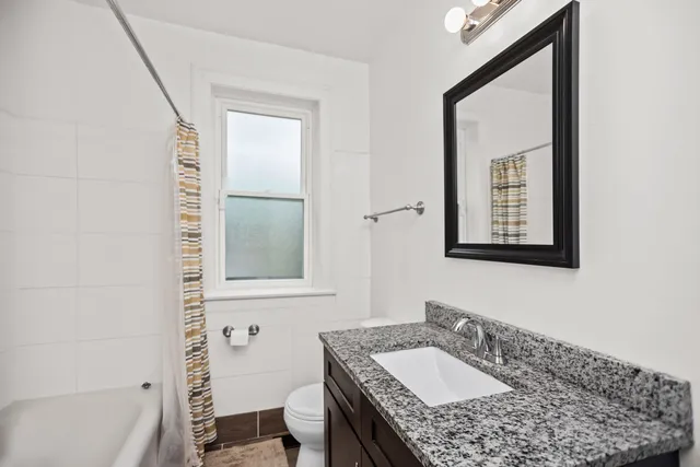a bathroom with a granite countertop sink toilet and mirror