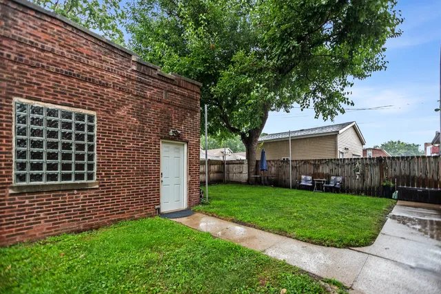 a view of a house with a yard plants and large tree