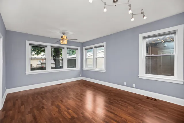 a view of an empty room with a window and wooden floor