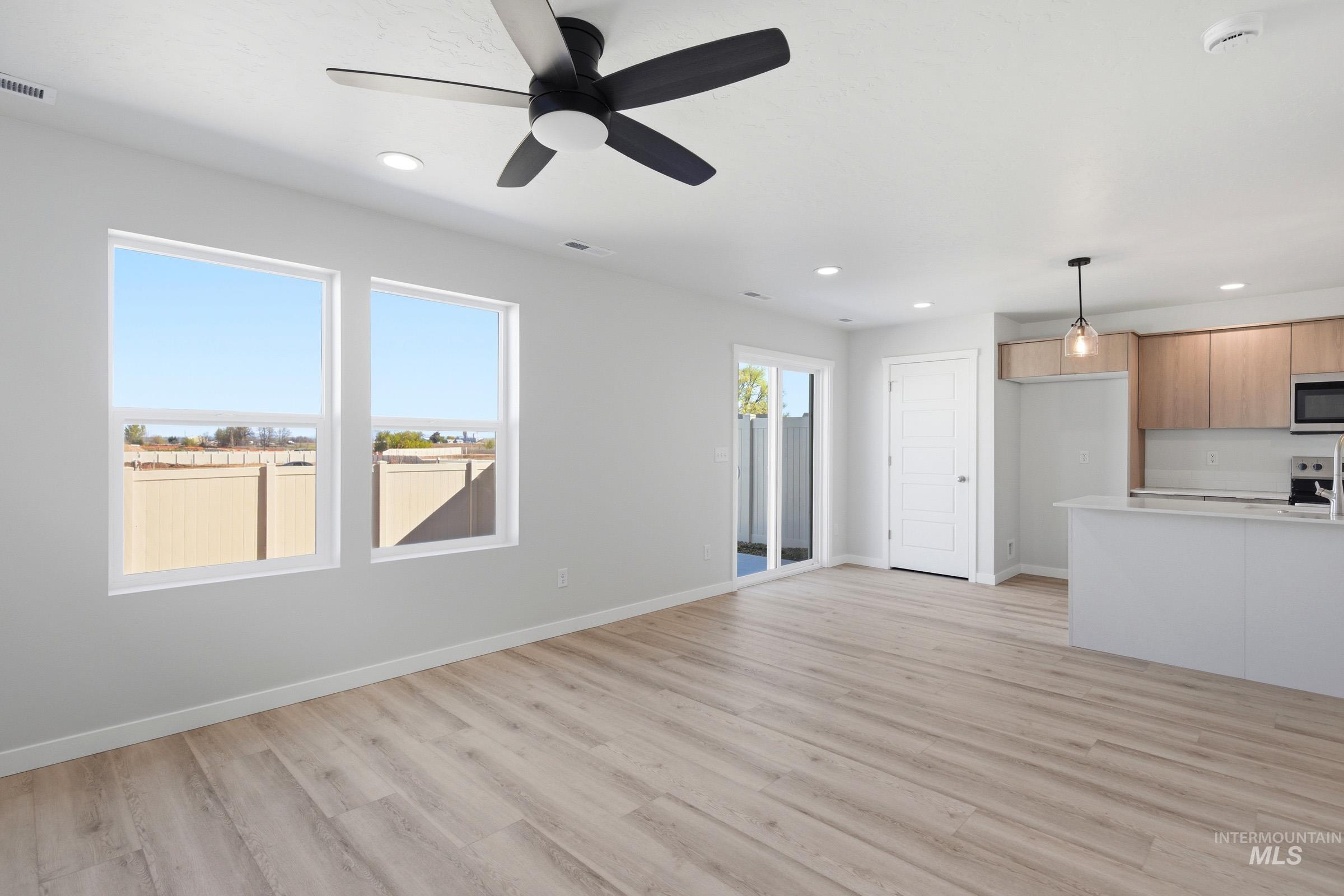 10812 Rutland Street Caldwell, ID 83605 - Photo 10 of 21 Open-concept living space featuring wood-finish flooring, a modern ceiling fan, recessed lighting, and large windows