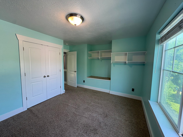 922 North 480 West Logan, UT 84321 - Photo 10 of 11 Carpeted interior space featuring a double-door closet, built-in shelving, a window with blinds, and white trim