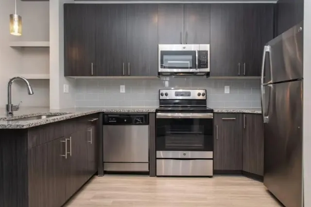 a kitchen with granite countertop a refrigerator and a stove top oven