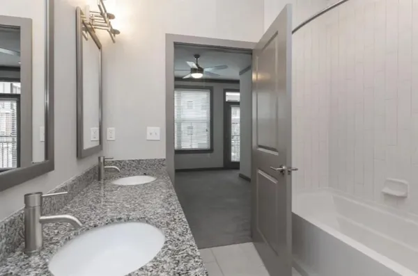 a bathroom with a granite countertop sink a mirror and a bathtub