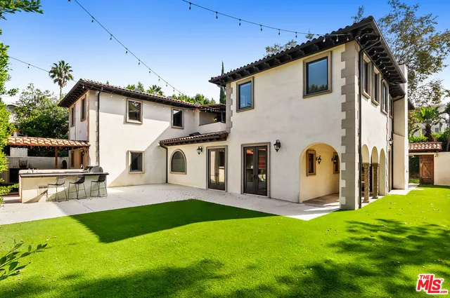 a view of a white house with a big yard potted plants and a table
