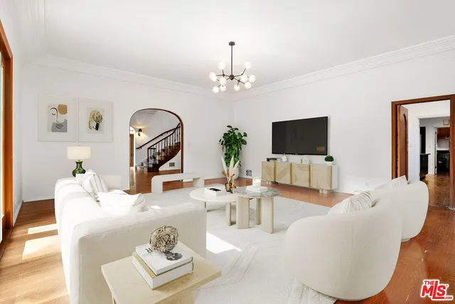 a living room with furniture a flat screen tv and a chandelier