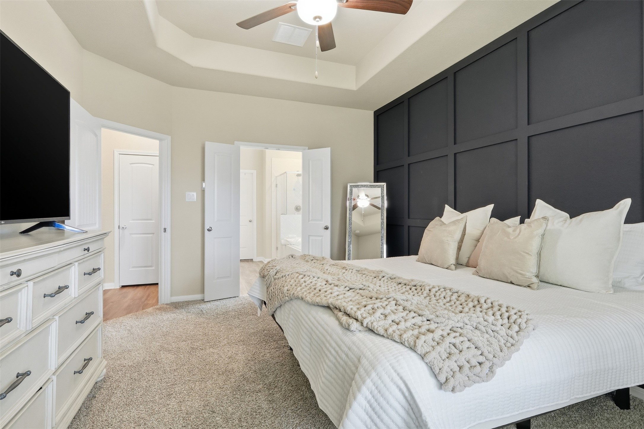 6310 Fawn Path Drive Conroe, TX 77303 - Photo 9 of 41 Private primary retreat featuring a stylish accent wall, plush carpeting, ceiling fan, and direct access to the luxurious en-suite bathroom.