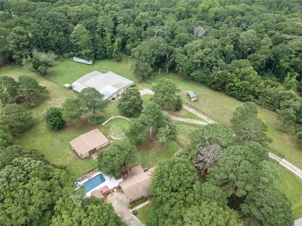 an aerial view of residential house with outdoor space and trees all around
