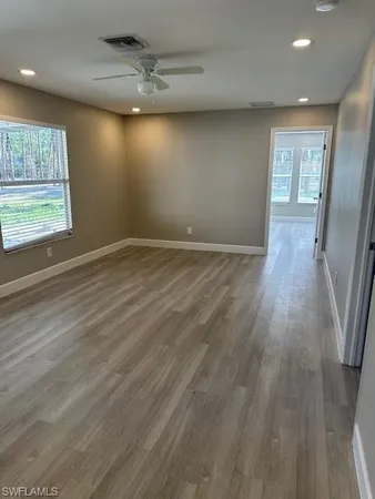 an empty room with wooden floor and windows