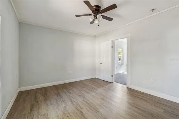 an empty room with wooden floor and a ceiling fan