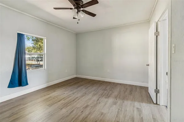 a view of a room with wooden floor fan and windows