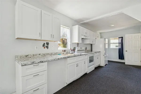 a kitchen with granite countertop white cabinets white stainless steel appliances with a sink and dishwasher