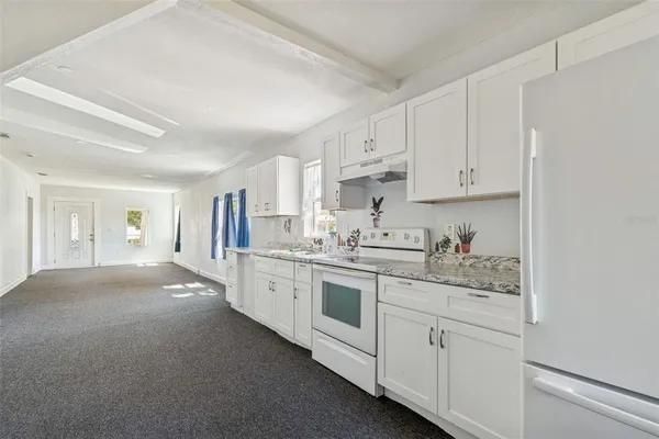 a kitchen with granite countertop white cabinets and white appliances