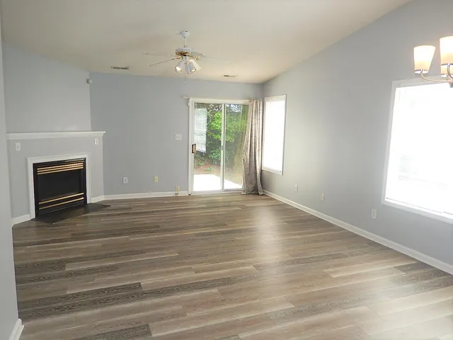 an empty room with wooden floor fireplace and windows