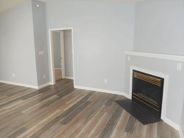 a view of empty room with wooden floor and fireplace
