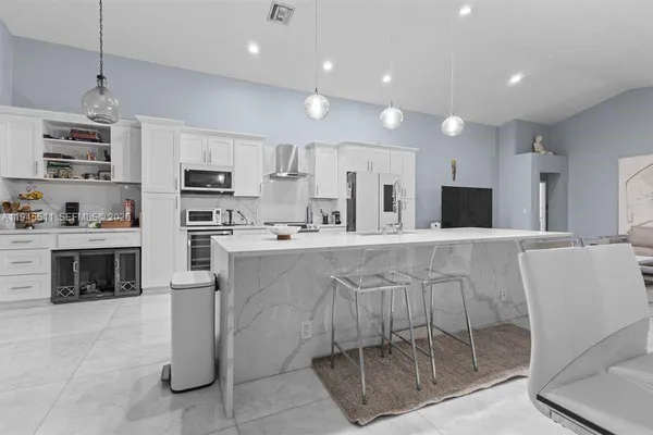 a kitchen with kitchen island granite countertop a refrigerator oven a sink a stove a dining table and chairs