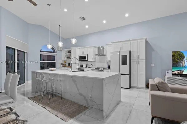 a large kitchen with stainless steel appliances a refrigerator a stove a sink a dining table and chairs
