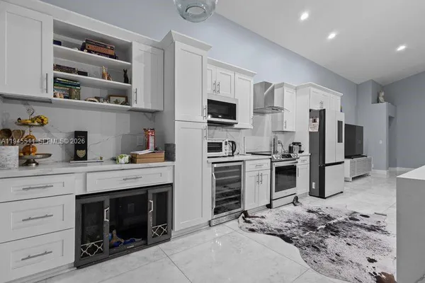a kitchen with stainless steel appliances kitchen island granite countertop a refrigerator oven a stove with cabinets and wooden floor