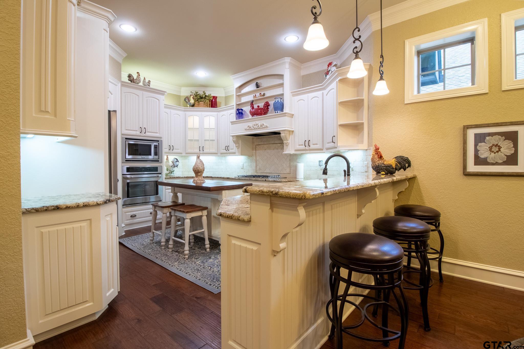 7315 Princedale Tyler, TX 75703 - Photo 6 of 25 a kitchen with stainless steel appliances granite countertop a stove top oven a sink a dining table and chairs with wooden floor