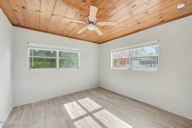 a view of an empty room with a window and wooden floor
