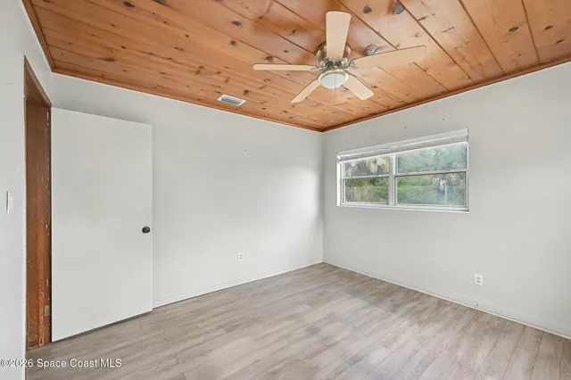 an empty room with a ceiling fan and window