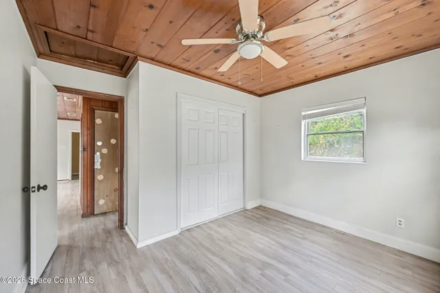 an empty room with wooden floor closet and windows