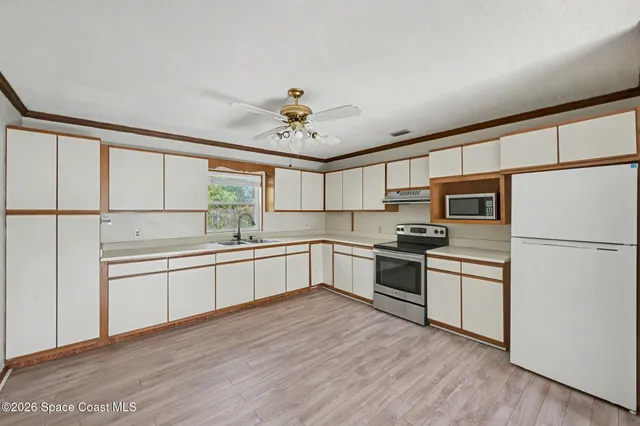 a kitchen with stainless steel appliances granite countertop a refrigerator a stove a sink dishwasher and white cabinets with wooden floor