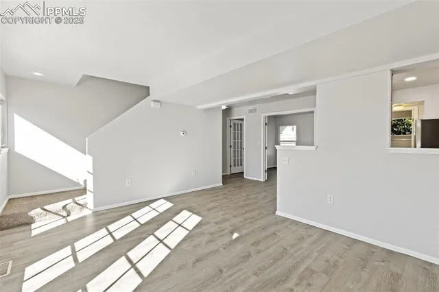 a view of a big room with wooden floor and windows