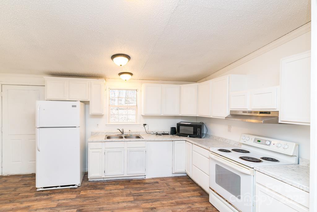 7368 Martins Creek Road Murphy, NC 28906 - Photo 10 of 21 a kitchen with a refrigerator a stove a sink and white cabinets with wooden floor