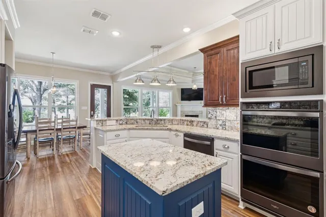 a kitchen with granite countertop kitchen island wooden cabinets and stainless steel appliances